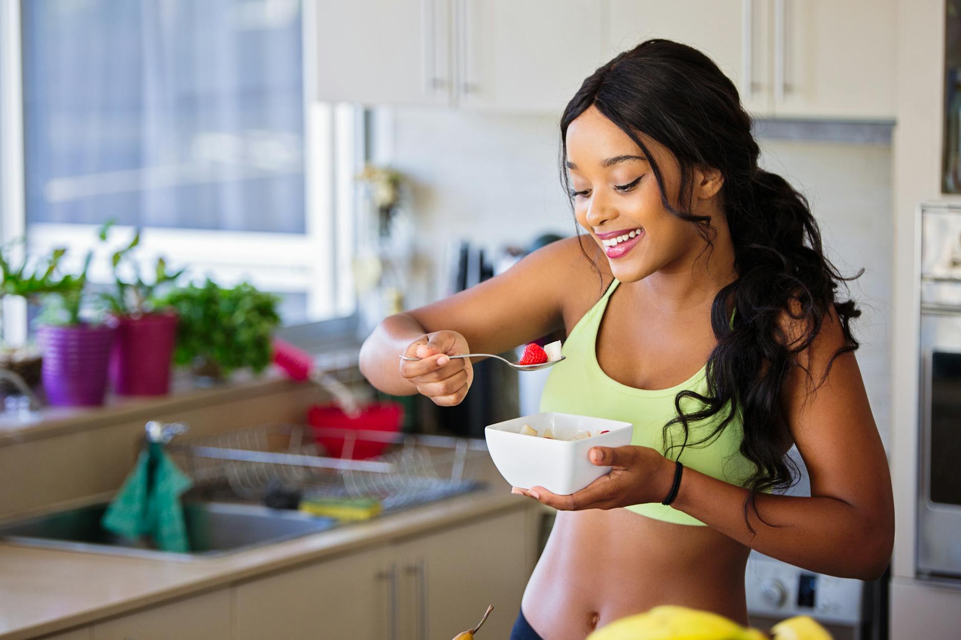 woman eating strawberry in the kitchen - Modèle Photo Fitness